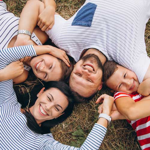 A family laying on the grass smiling