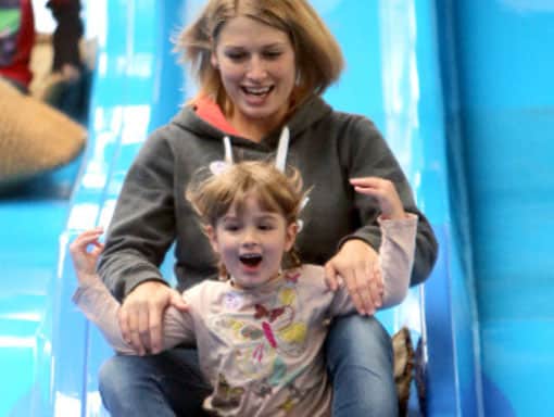 Mother and daughter on a slide having fun in the bad weather